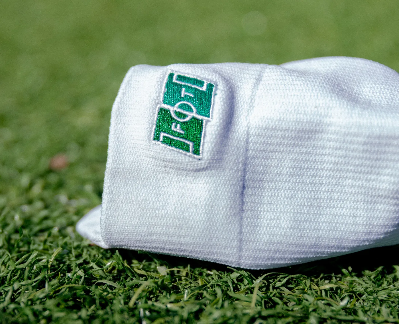 A close-up of the grip sock cuff, with the First Touch to First Team pitch mark embroidered in green on white